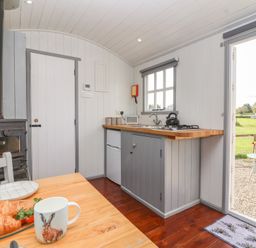 A kitchen with stove and dining table at The Shepherds Hut in Chippenham