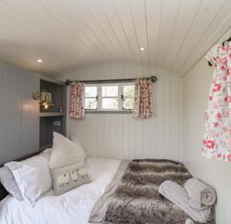 A bedroom with a bed and window at The Shepherds Hut in Chippenham