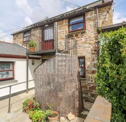 An exterior view of a stone building with a spiral staircase and potted plants at The Stables in Longrock