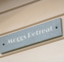 A sign with the text Moggs Retreat on an exterior wall at Moggs Retreat in Chapel St Leonards