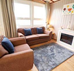 A living room with a sofa and fireplace at Moggs Retreat in Chapel St Leonards