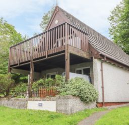 A house with a wooden balcony and garden surrounded by trees at Valley Lodge 52 Callington