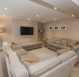 A living room with grey sofas a wall-mounted television and floor lamps at Station House in Scarborough