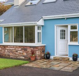 The exterior of a blue house with a white door stone wall base and potted plants at The Blue Annex The Spa near Tralee County Kerry