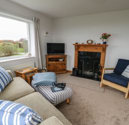 A living room with a sofa and television at Yr Orsedd in Llanfaethlu