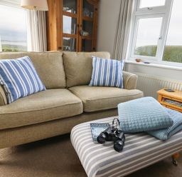 A living room with a sofa, coffee table, and binoculars at Yr Orsedd, Llanfaethlu