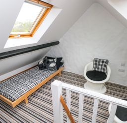 An attic room with a single bed and two chairs with cushions at The Old Stables in Fishguard