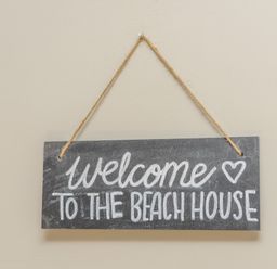 A hanging sign with welcome to the beach house text on a beige wall at 39 Longbeach Drive in Beadnell