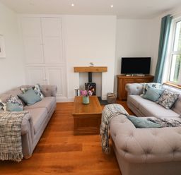 A living room with two sofas a wooden coffee table and a television at Copybush Cottage in Lawrenny