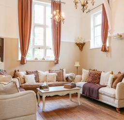 A living room with sofas pillows and a coffee table in front of windows with curtains at The Old School in Downham Market
