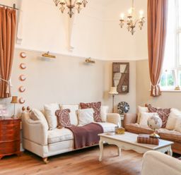 A sitting room with sofas cushions coffee table and windows with curtains at The Old School in Downham Market