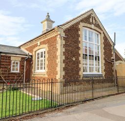 Exterior of a building with large windows black metal fence and grass at The Old School in Downham Market