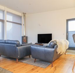 A living room with leather sofas a wood floor a television and a window with blinds at Idlewild 2 Wheal Turnavore in St Agnes