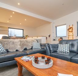 A living room with two black leather sofas and a wooden coffee table at Idlewild 2 Wheal Turnavore in St Agnes