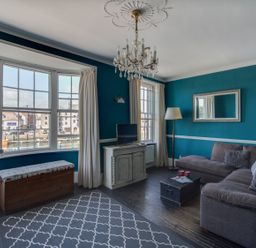 A living room with a gray sectional sofa a wooden chest and a patterned rug at Sailor's Watch in Weymouth