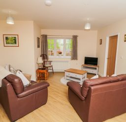 A living room with brown leather sofas a coffee table a tv and a window at Ryedale Country Lodges - Hazel Lodge Kirkbymoorside