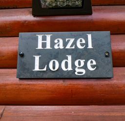 A sign displaying the name Hazel Lodge on a wooden wall at Ryedale Country Lodges - Kirkbymoorside