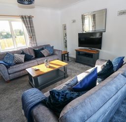 A living room with two sofas cushions a coffee table a television and curtains at The Old Well Bungalow - Ty Mawr Farm Cardiff