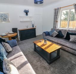 A living room with two sofas a wooden coffee table a sideboard and a dining table with chairs at The Old Well Bungalow - Ty Mawr Farm Cardiff