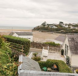 A coastal view with houses and a sandy beach in the background at Castell in Abersoch