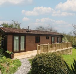 A cabin with a deck and landscaping at Castell Chalet in Penrhos near Pwllheli