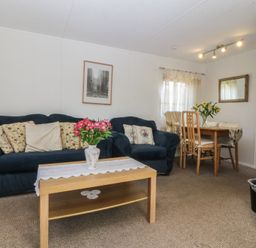 A living room with a sofa and dining table at Castell Chalet in Penrhos near Pwllheli