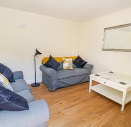 A living room with two blue sofas a white coffee table and a wall mirror at Puddleducks in Sherborne