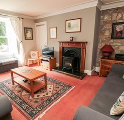 A living room with sofas a wooden coffee table a fireplace and a window at Simonside Apartment in Rothbury