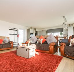 A living room with brown leather sofas red cushions and a red rug at Bear Cottage in Chacewater near Truro