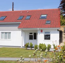 A house with a red tiled roof and white walls with windows and garden at The Crest in Helston