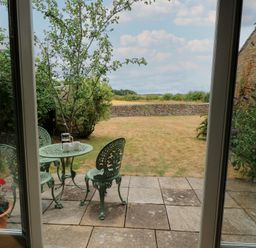 A garden with a table and chairs looking out at the fields at The Lodge at Mortons in Hankerton