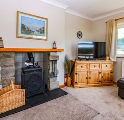 A living room with a fireplace and television at Pen Y Garth Mynytho near Llanbedrog
