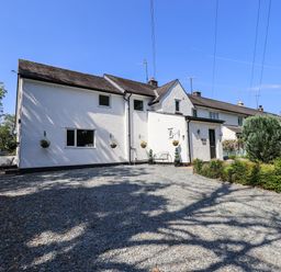 A white exterior house with a gravel driveway and plants at Ellerbeck Bridge in Underbarrow near Kendal