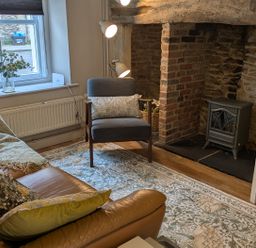A living room with a sofa, chair, and fireplace at Troopers Cottage in Frome