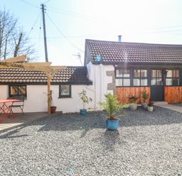 A gravel courtyard with potted plants and a seating area with table and chairs at Toadstools Rame Cross near Penryn