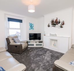 A living room with two sofas a recliner chair a television and a decorative wall hanging at Quayside View in Brixham