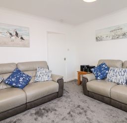 A living room with two sofas with blue and white cushions and two paintings on walls at Quayside View in Brixham
