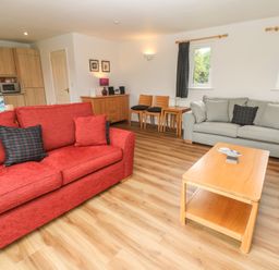 A living room with two sofas a wooden coffee table and a sideboard with chairs at 64 Waterside in Lanivet