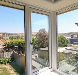 A view of rooftops trees and hills through corner windows at Thorncroft in West Bay