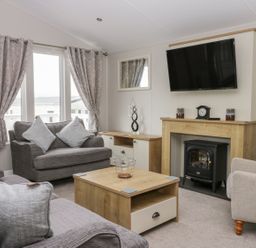 A living room with sofas a coffee table a fireplace and a mounted television at Cayton Pines Cayton Bay near Scarborough