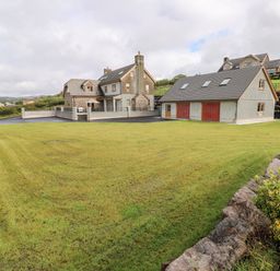 A large yard with green grass and two houses in the background at Grooms Quarters at Pant y Gaseg Farm in Ammanford