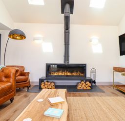 A living room with a fireplace a leather sofa a wooden coffee table and a television at See Two Seas Cape Cornwall in St Just