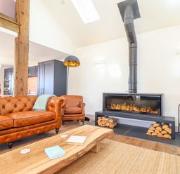 A living room with a leather sofa armchair wood coffee table and a fireplace at See Two Seas Cape Cornwall in St Just