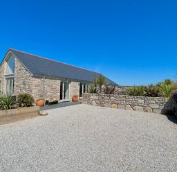 A stone house with slate roof and gravel driveway surrounded by stone walls and plants at See Two Seas Cape Cornwall in St Just