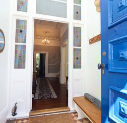 A hallway with a blue front door and a bench at Holcombe House in Torquay