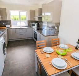 A kitchen with counters appliances and a dining table set for four at Mill View in Neyland