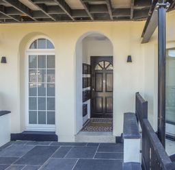 An outdoor entrance area with a black door white window tiled floor and black railings at Harbour View Apartment in Looe