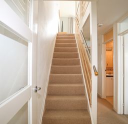 A staircase with carpet leading to an upper floor next to a hallway with doorways opening to other rooms at Delfryd in Y Felinheli