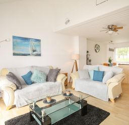 A living room with two sofas and a glass coffee table next to an open kitchen at Delfryd in Y Felinheli