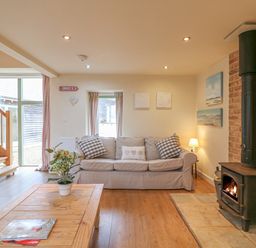 A living room with sofas a wooden coffee table plant a wood burning stove and stairs at The Apple Barn at Wyke Farm in Lyme Regis
